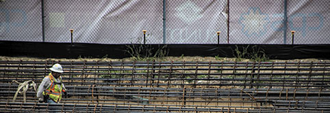 After receving Lean learning for trade partners, a worker in a hardhat and safety vest traverses through the job site.